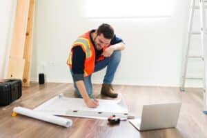 Floor & wall tile Installer | cheerful latin architect smiling while looking online information laptop working construction plans